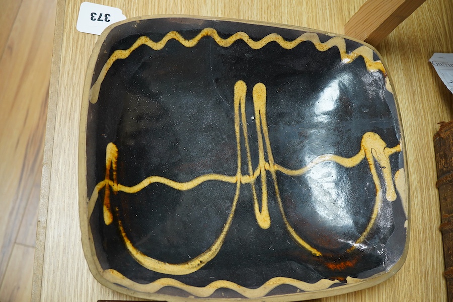 A 19th century pottery slipware baking dish (restored), 34cm wide and a Spanish maiolica tile